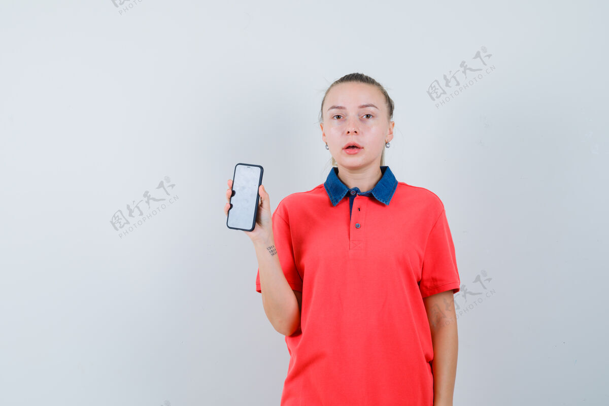 年轻一个穿着t恤展示手机的年轻女子 看上去很困惑人物肖像正面