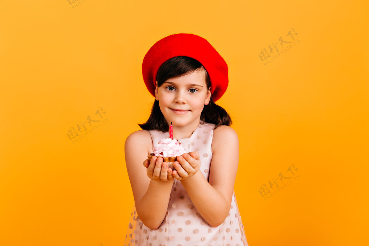 脸幸福的孩子在庆祝生日黄色墙壁上隔离着蛋糕的未成年女孩的正面视图庆祝黑发可爱