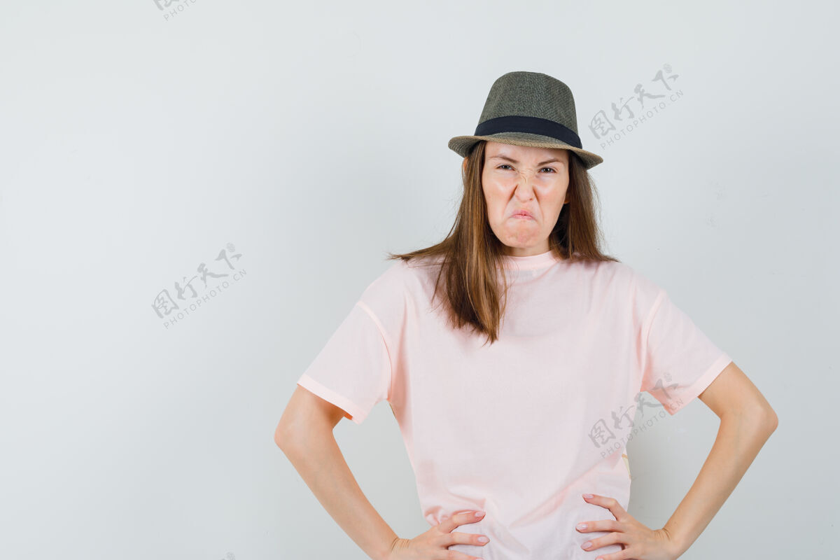 连衣裙穿着粉色t恤 戴着帽子的年轻女士双手放在腰上 看起来很恶毒 正面照友谊帽子女人