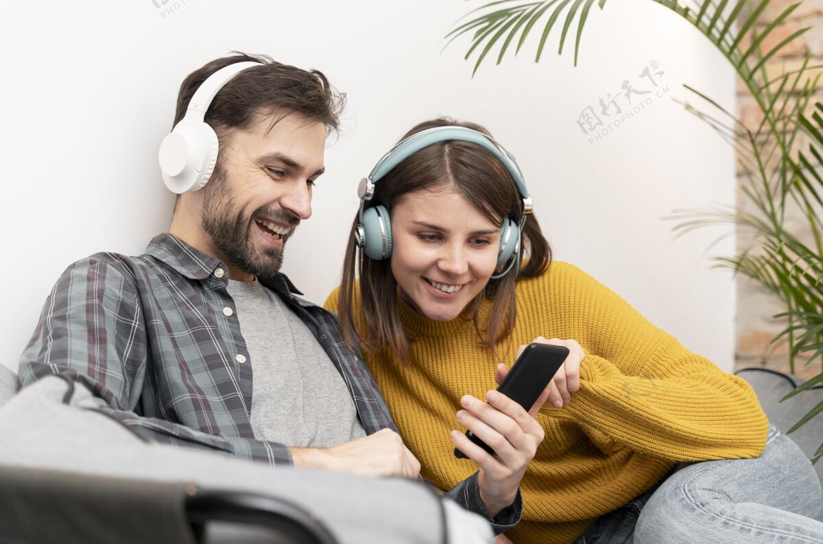 女人情侣们在听音乐耳机在一起在家里的乐趣