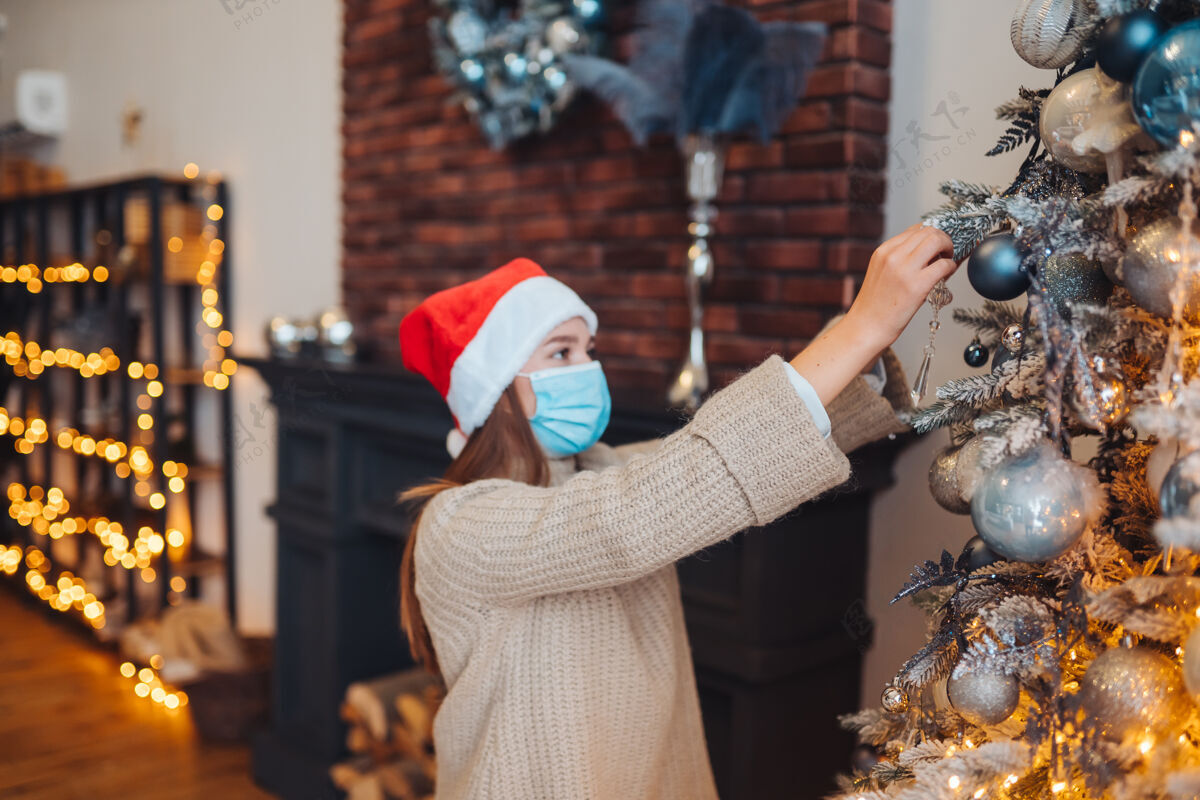 女人一个年轻女子用医用面具装饰圣诞树圣诞节新的准备