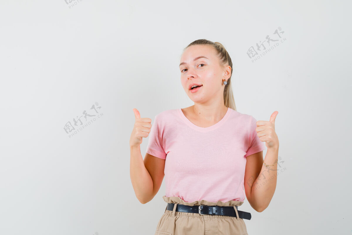 肖像金发女性 穿着t恤 裤子 竖起大拇指 看起来很快乐 正面视图女性双人人