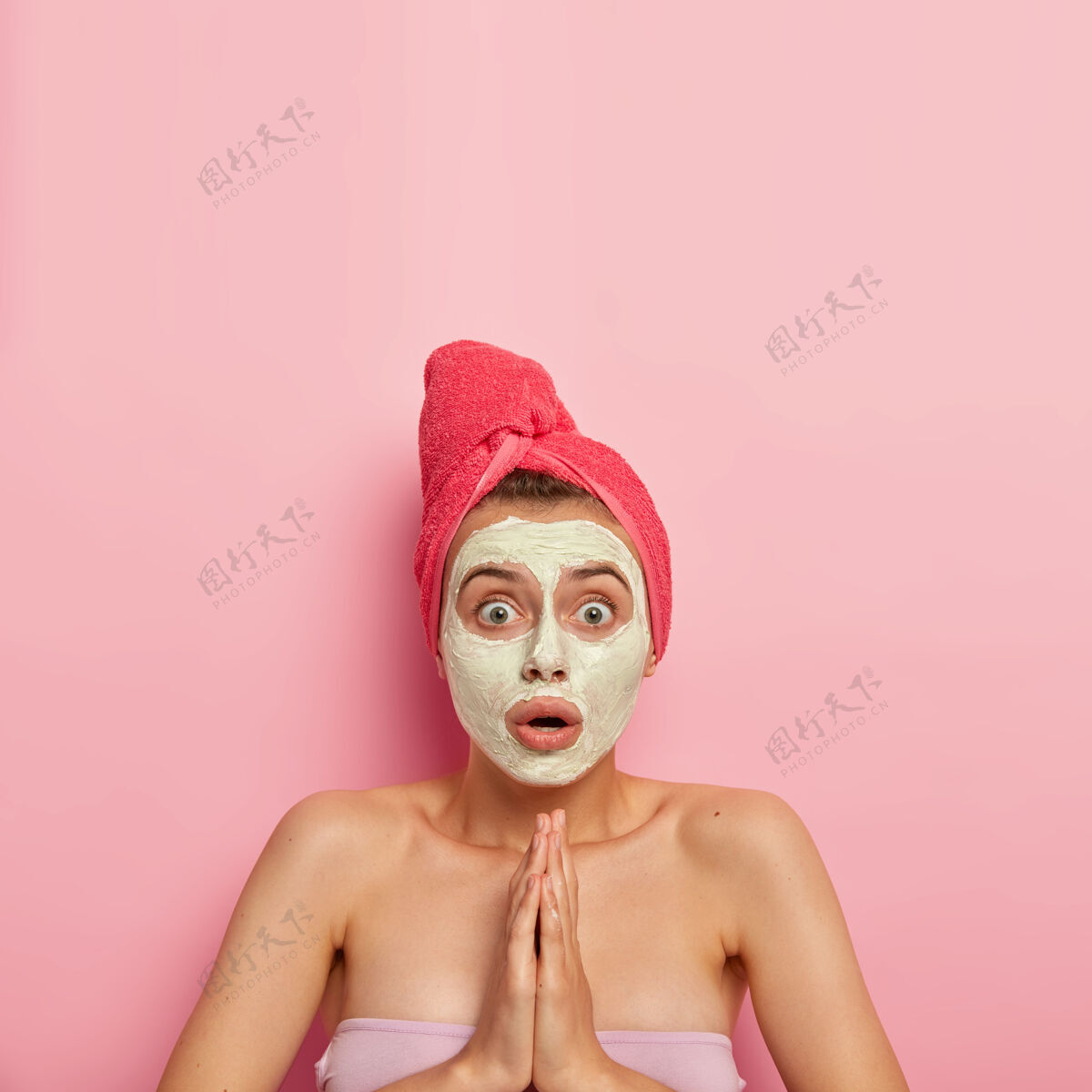 化妆品无助震惊的女人双手紧握 屏息凝望 询问如何更好地护理肤色和皮肤 在脸上涂上天然粘土面膜 用毛巾包着无助幸福健康