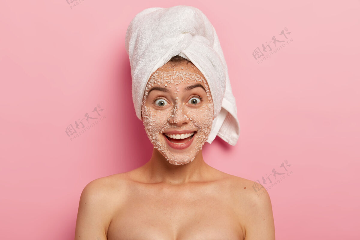 女人面部护理可爱快乐的女人 带着迷人的微笑 去除脸上的毒素和黑头 应用天然的白色海盐颗粒磨砂 拔出木屐 拥有赤裸裸的精心呵护的身体毛巾盐化妆品