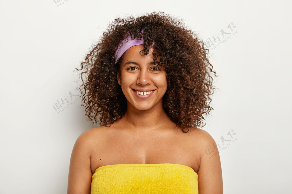 室内美丽快乐的非洲裔妇女站在黄色毛巾里 准备洗桑拿 浓密清爽的头发 戴着头带 满足于看起来永远年轻女性 种族和幸福的概念非洲卫生淋浴