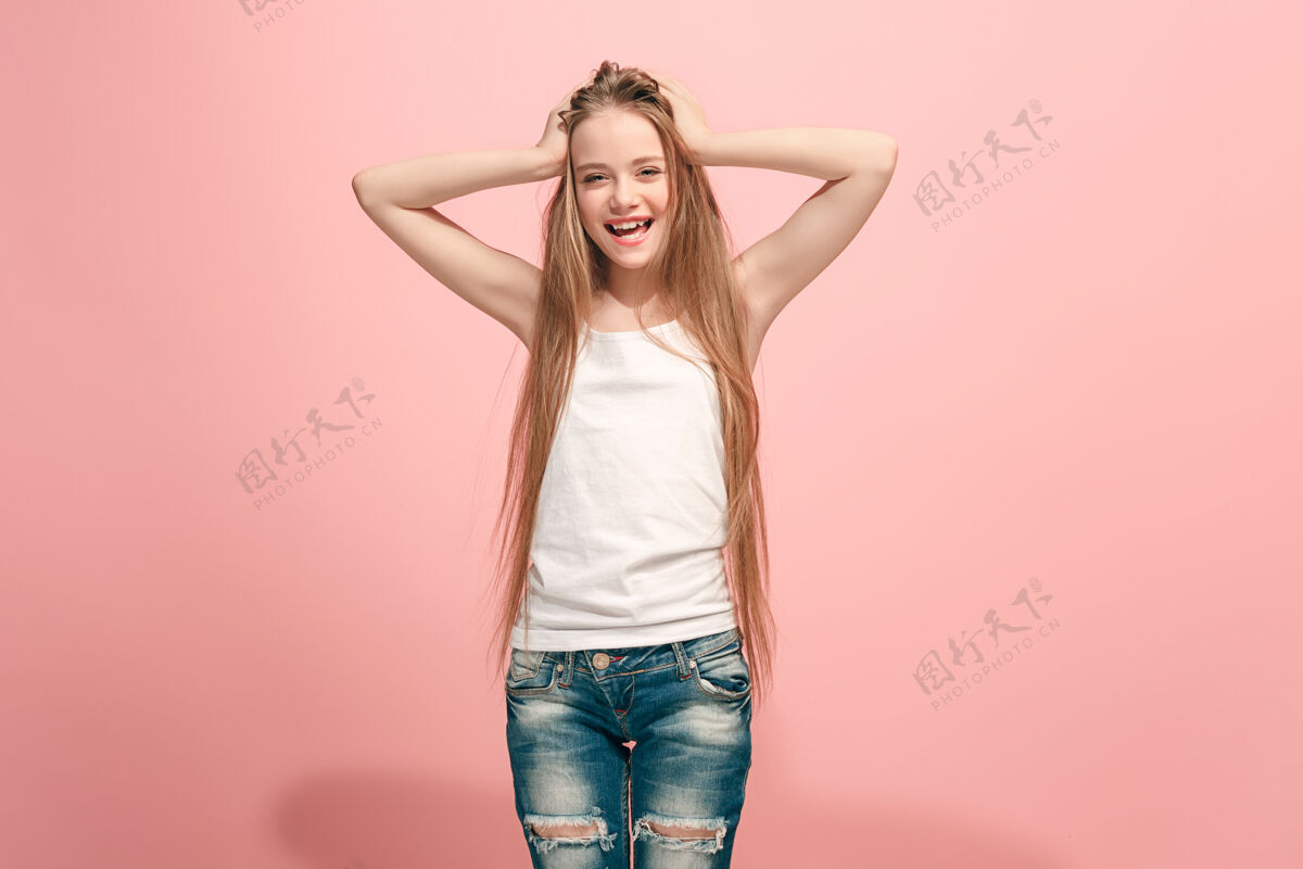成人快乐的少女站在时尚的粉色工作室背景上 微笑着美丽的女性半身像人类的情感 面部表情的概念魅力漂亮青少年