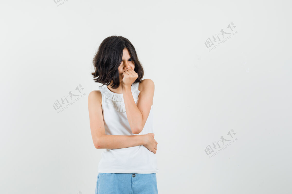 站立小女孩站在思考的姿势在白色衬衫 短裤和看起来阴郁 前视图青年青少年衬衫