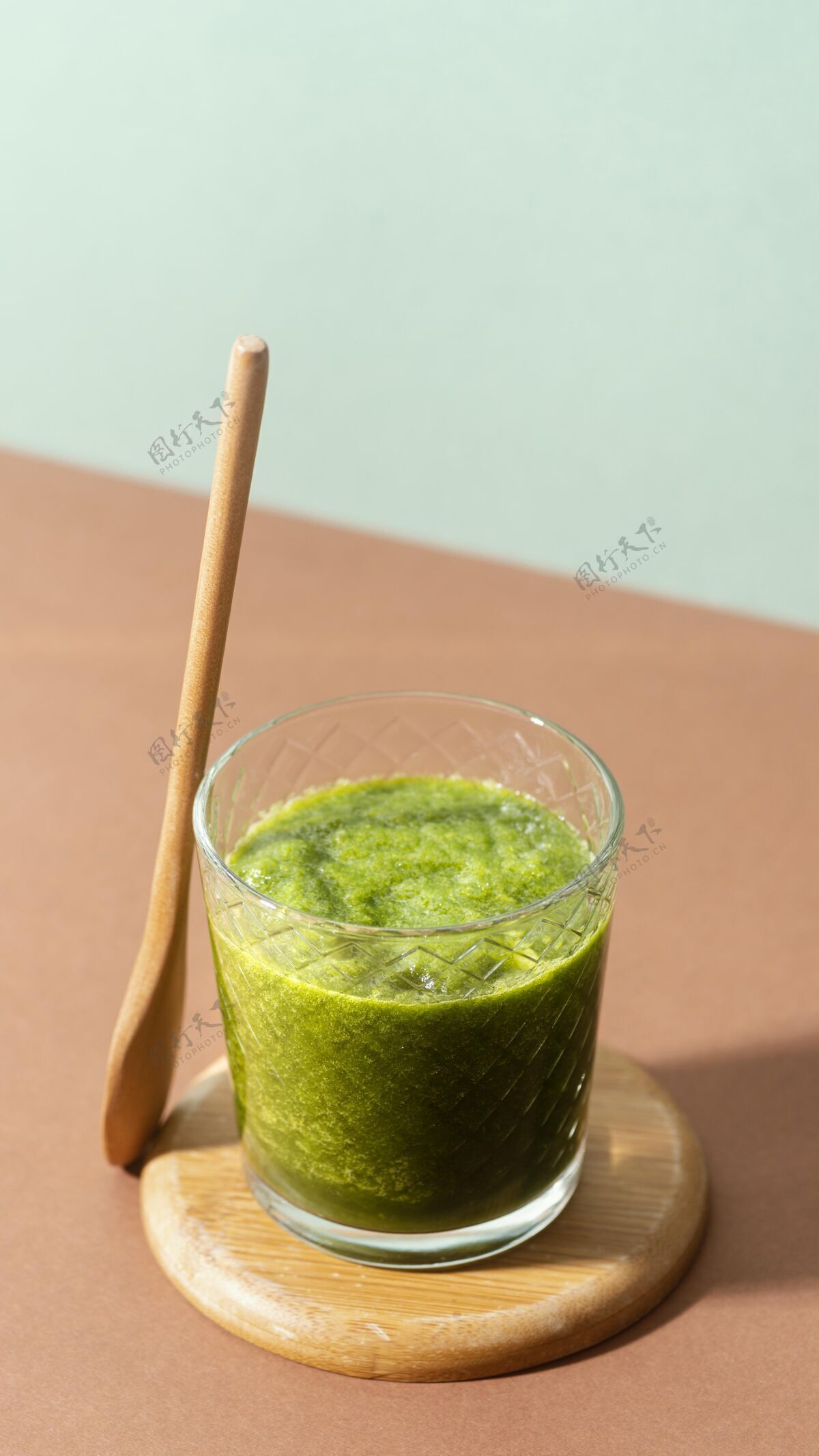 垂直高角度绿色冰沙和木勺健康玻璃饮料