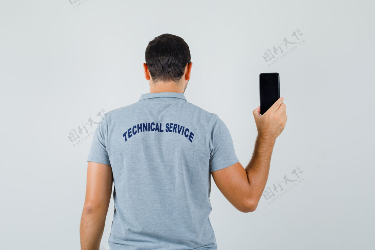 人年轻的技术人员转过身来 展示着他身着灰色制服的手机 看上去很优雅系统专业灰色