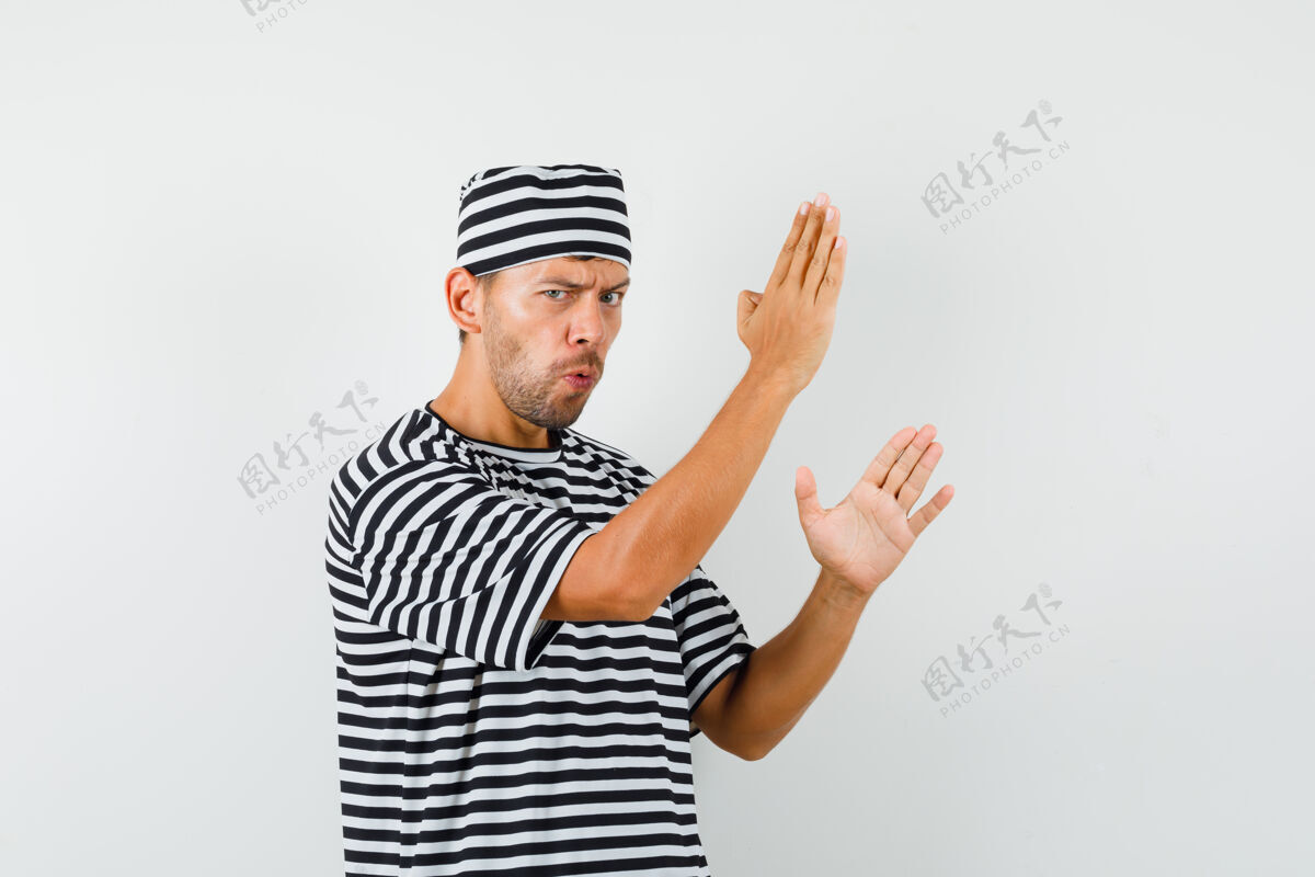 朋友一个年轻人穿着条纹t恤 戴着帽子 展示着空手道砍人的动作 看上去很有力量帽子男人脸