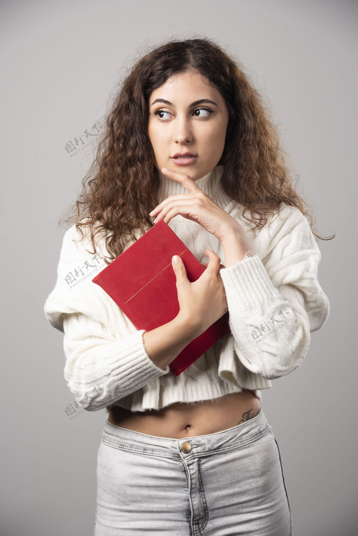 人在灰色的墙上拿着红皮书的年轻女子高质量的照片年轻女孩女性