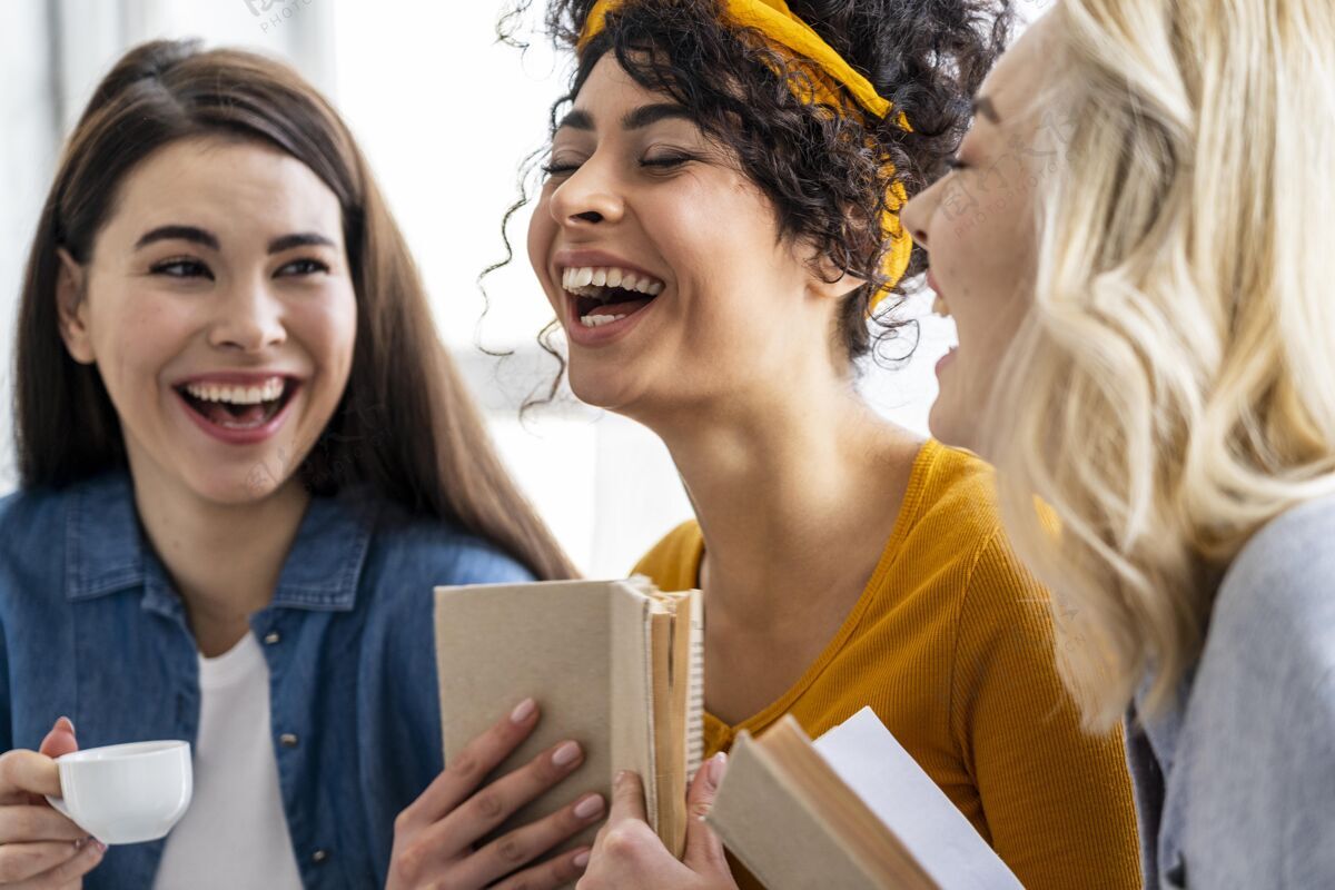 庆祝三个女人拿着书和咖啡一起笑积极全球国际
