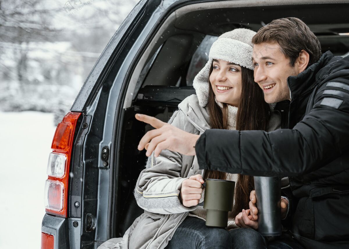 饮料一对夫妇在公路旅行时在汽车后备箱里喝热饮的正面图热水瓶户外指向