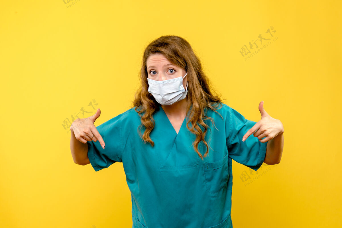 漂亮正面图黄色地板上戴着面罩的女医生医护人员-大流行黑发视图冠状病毒