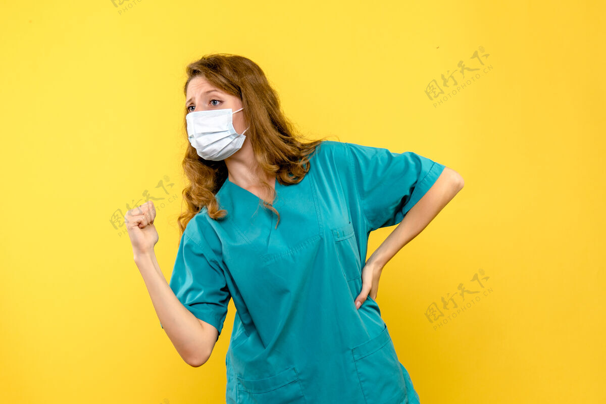 漂亮前视图年轻女医生戴着面具在淡黄色的空间里女人医学微笑