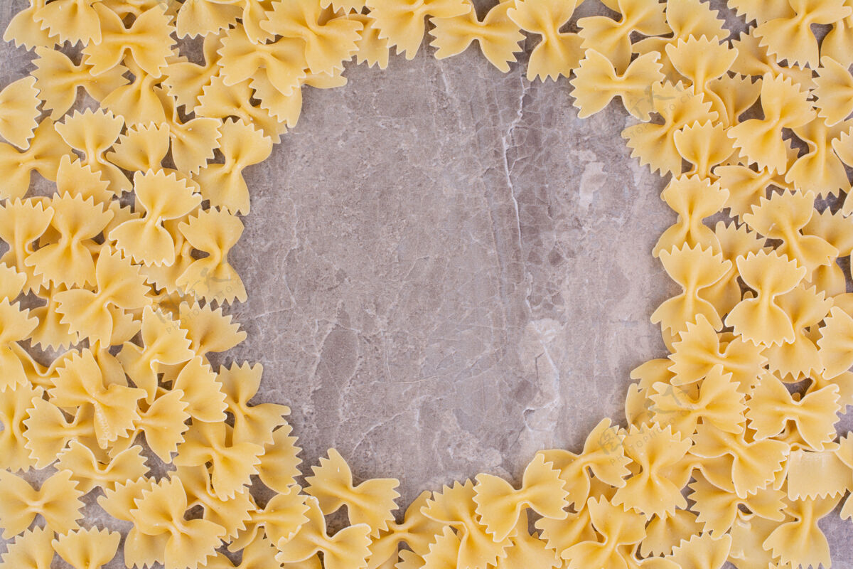 螺旋形生的和未煮熟的意大利面被隔离在大理石表面盘子极简健康