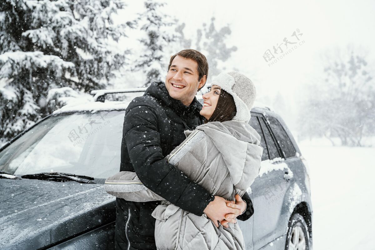 女人侧视图笑脸夫妇拥抱在雪地里 而在公路旅行航行自然旅行