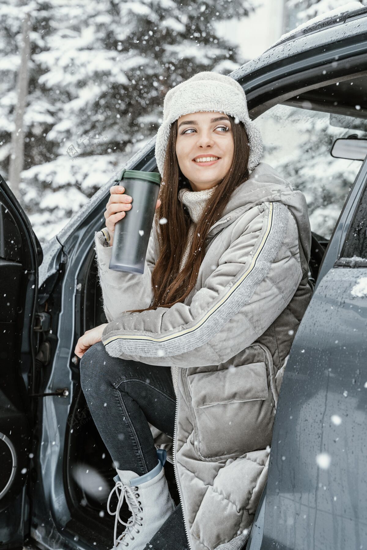 户外微笑的女人在路上享受雪户外汽车饮料
