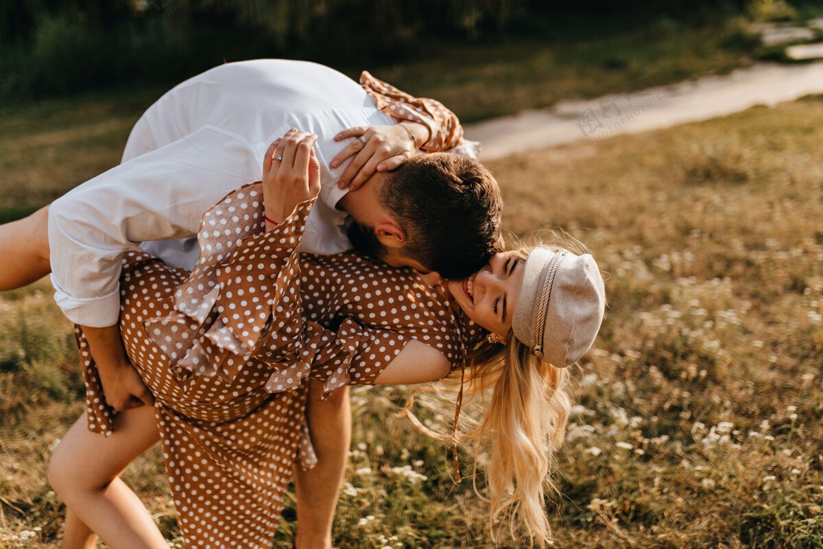 关系一对情侣在公园里鬼混夫妻拥抱 亲吻 玩得开心男性情侣棕色连衣裙