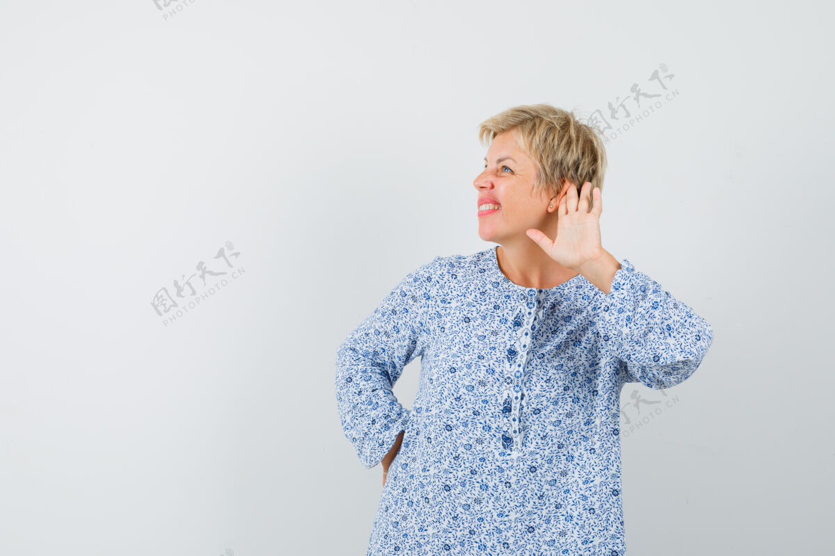 女人一个穿着衬衫的成熟女人把手放在耳朵后面 看起来很好奇活跃女人耳朵
