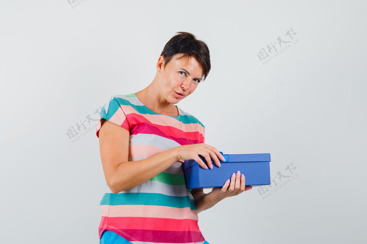 人穿着条纹t恤的女人试图打开礼物盒 看上去很好奇可爱休闲乐趣