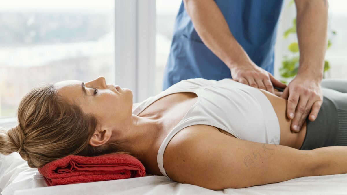 健康男性骨科治疗师检查女性患者腹部的正视图运动病人治疗师