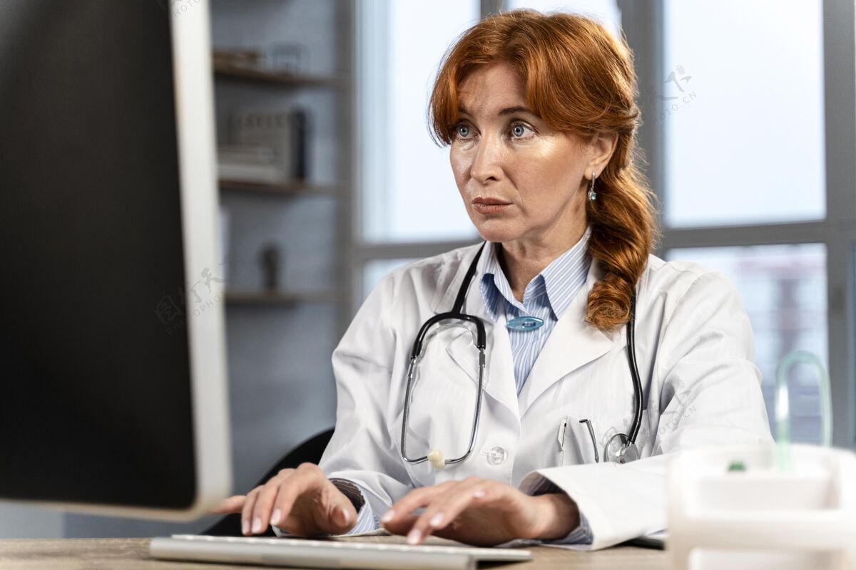 医生女医生在办公桌上的电脑上查找资料的正面图键盘工作医生