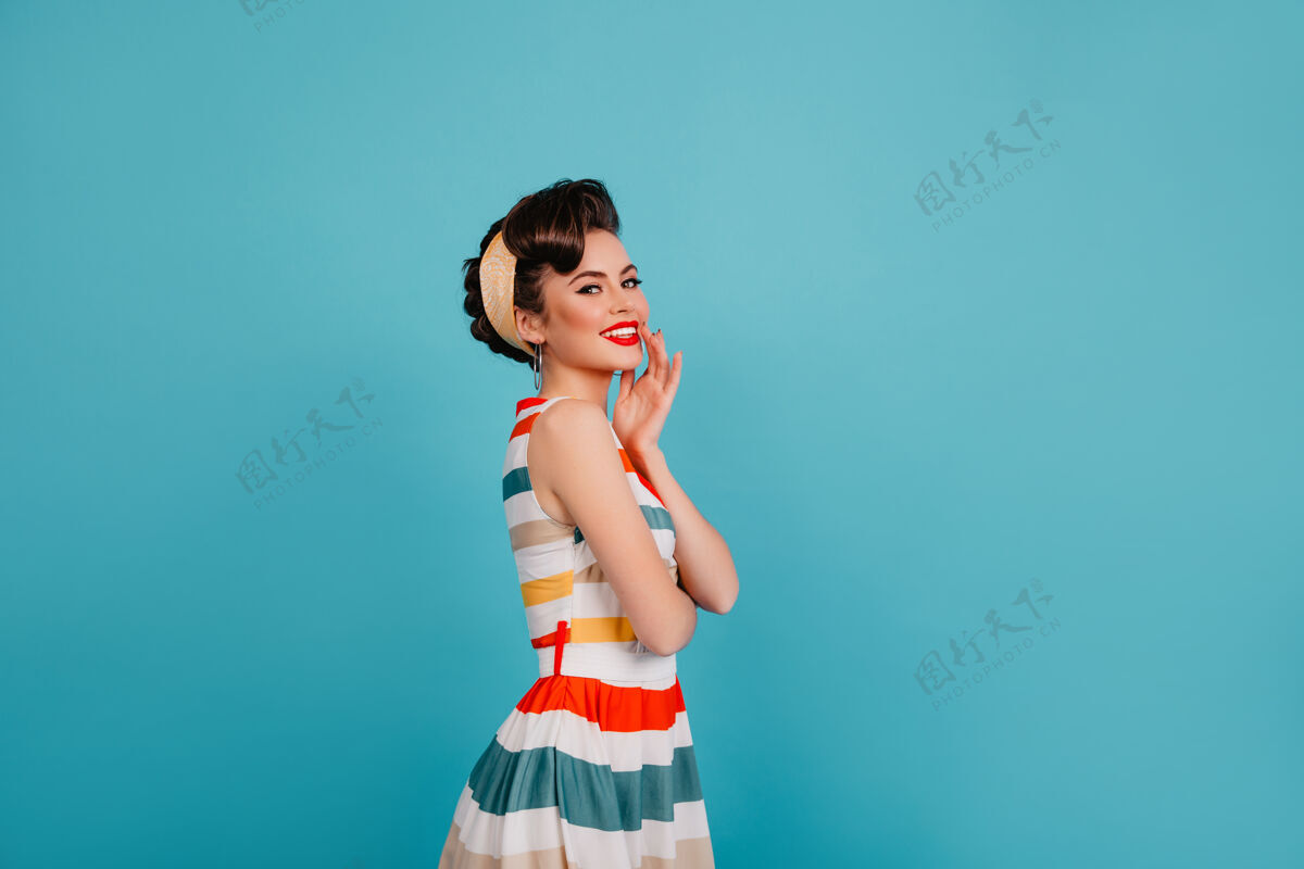 漂亮无忧无虑的优雅女人在明亮的裙子摆姿势摄影棚拍摄的时髦的小女孩在蓝色背景下大笑优雅舞蹈享受