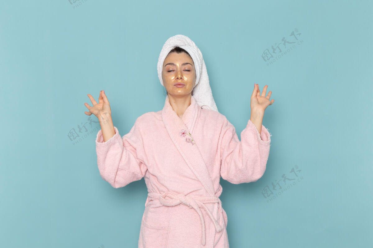 人正面图年轻女性穿着粉色浴袍淋浴后在蓝色墙上清洗美容洁面水自护霜淋浴肖像微笑年轻人