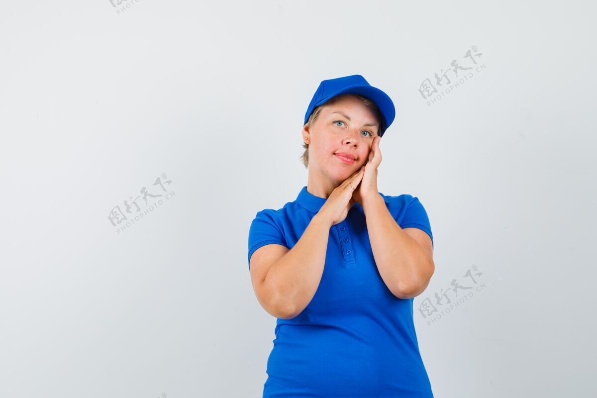 女性一个成熟的女人穿着蓝色t恤检查她的面部皮肤 看起来很优雅帽子肖像自信