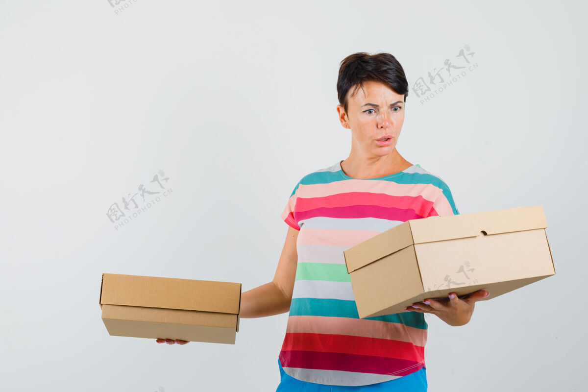 脸一个穿着条纹t恤的女人看着纸箱 看起来很困惑可爱时尚人
