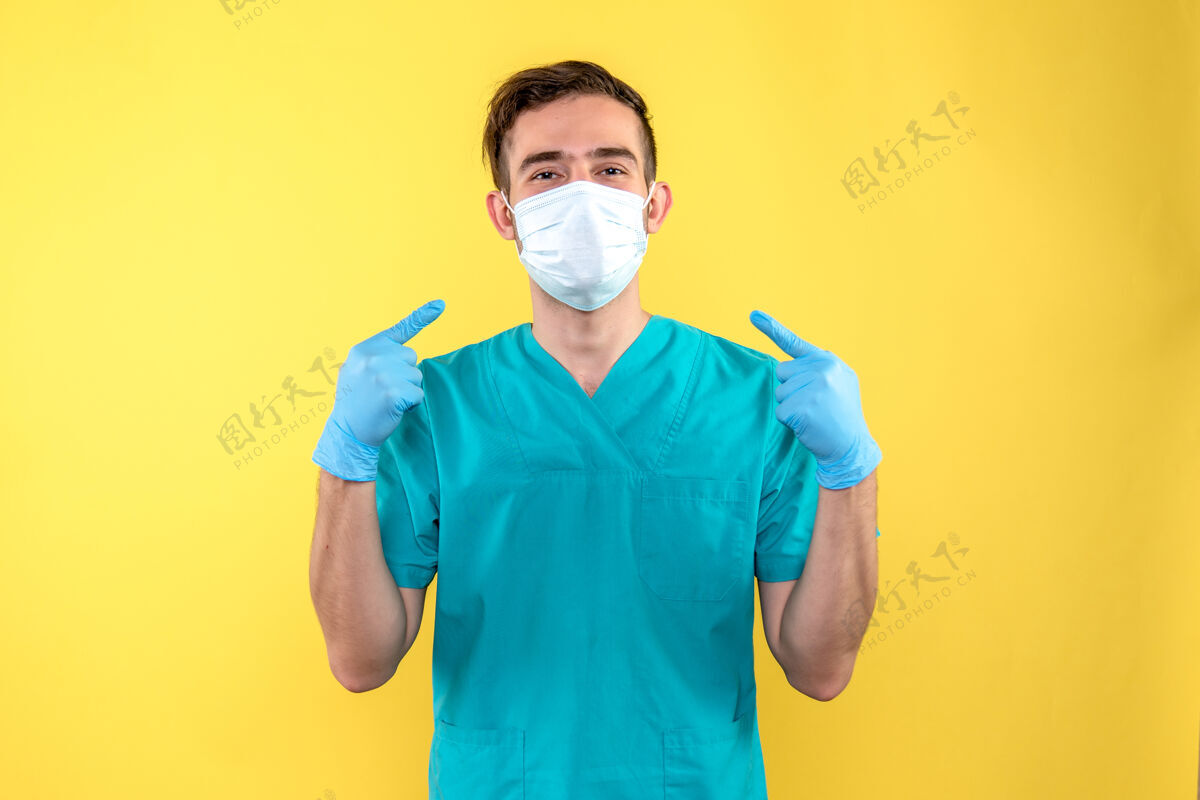 男性黄墙上戴着手套和口罩的男医生的正视图情绪正面人