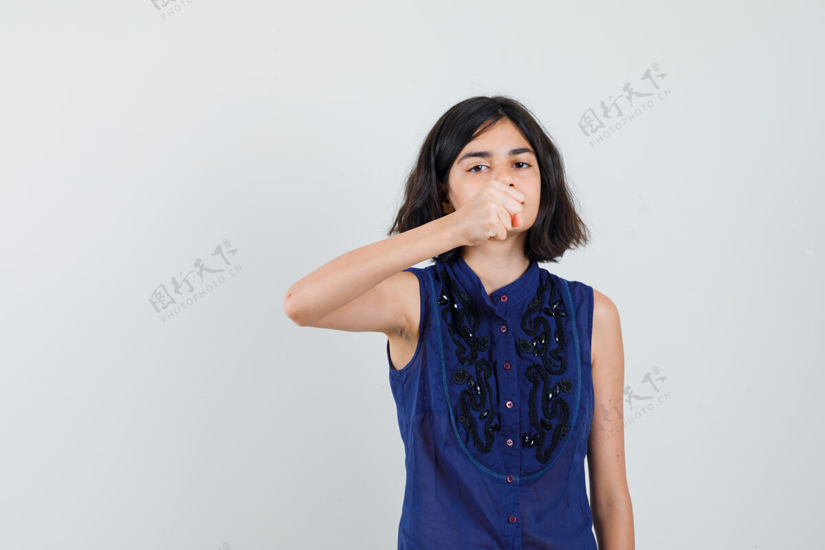 年轻穿蓝色上衣的小女孩握紧拳头威胁 神情严厉外观时尚小