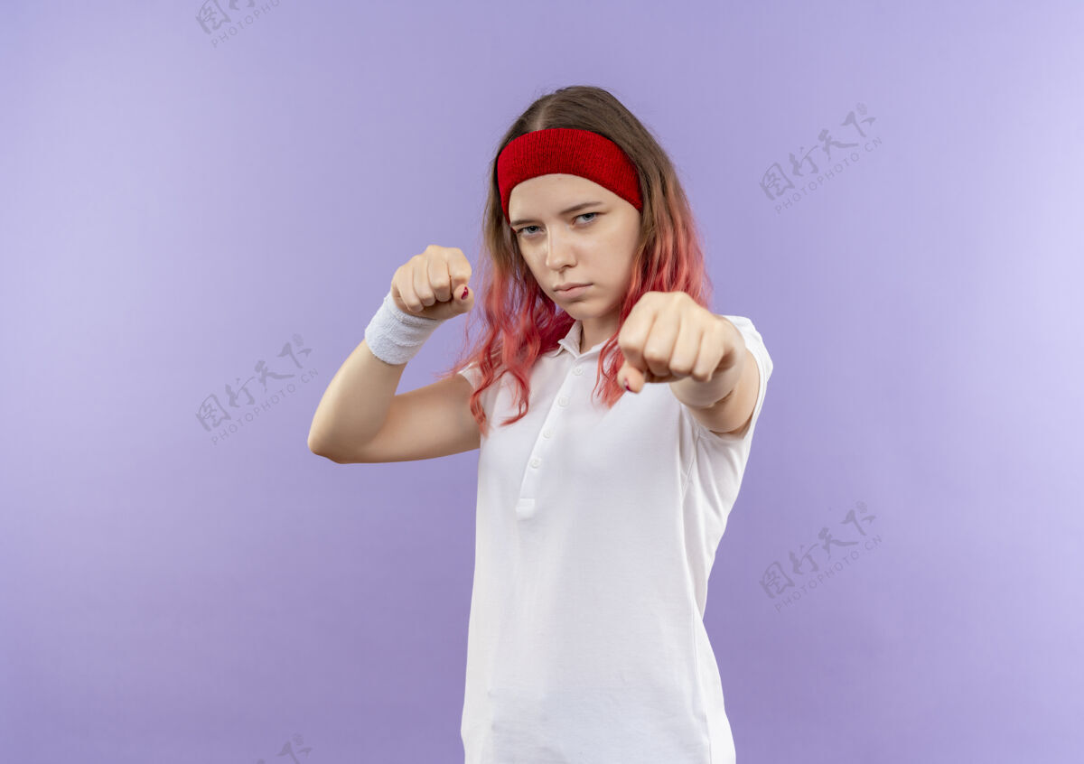 运动年轻的运动女孩站在紫色的墙上 摆出一副拳击手的姿势拳击手市民喜欢