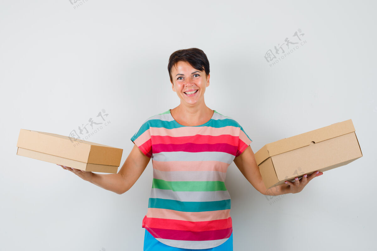 年轻一个穿着条纹t恤 裤子 拿着纸板箱 看起来很快乐的女人欢呼乐趣纸板