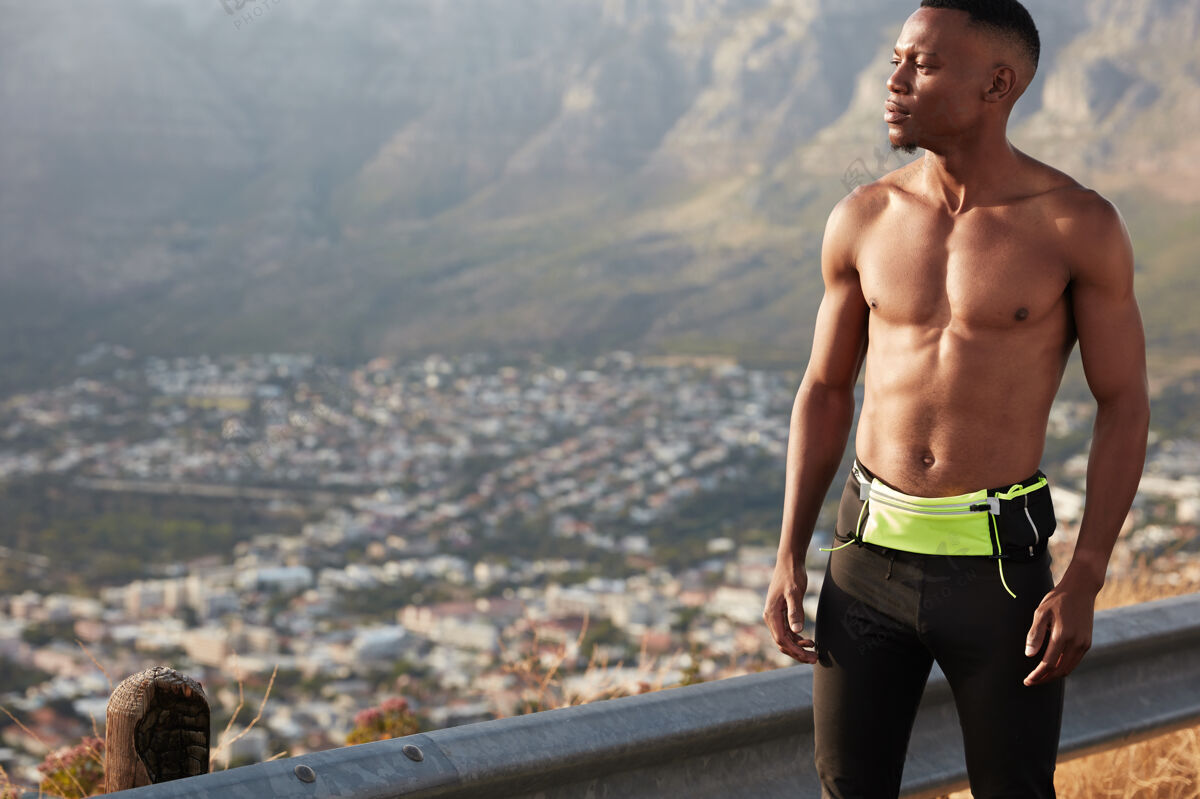 户外横向拍摄的自信的运动型男子 肌肉发达的身体 穿着运动服 有上午的锻炼 在外地 集中在远处的自由空间山地呼吸动机