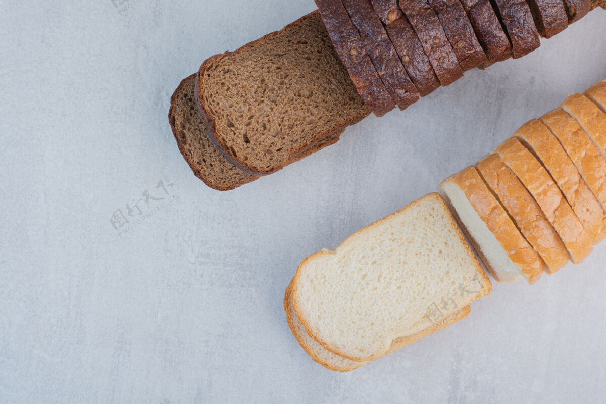 美味新鲜的白色和棕色面包片放在大理石背景上切片棕色糕点