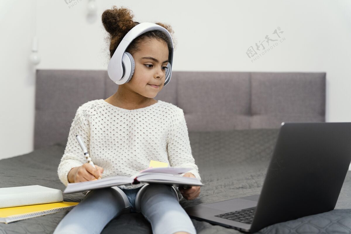 耳机小女孩用笔记本电脑和耳机上网上学在线班级小