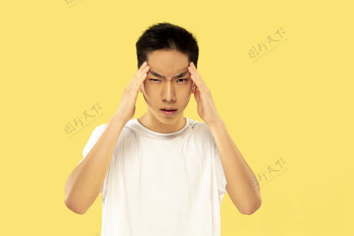 表情黄色工作室背景上的韩国年轻人半身像穿白衬衫的男模思维严肃人类情感的概念 面部表情正面视图流行色彩员工面部亚洲人