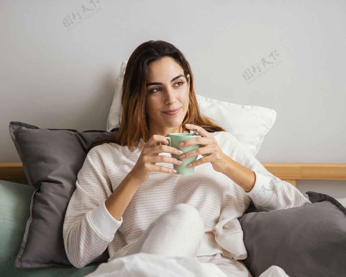 度假在床上喝咖啡的女人的前视图逗留住宿房子