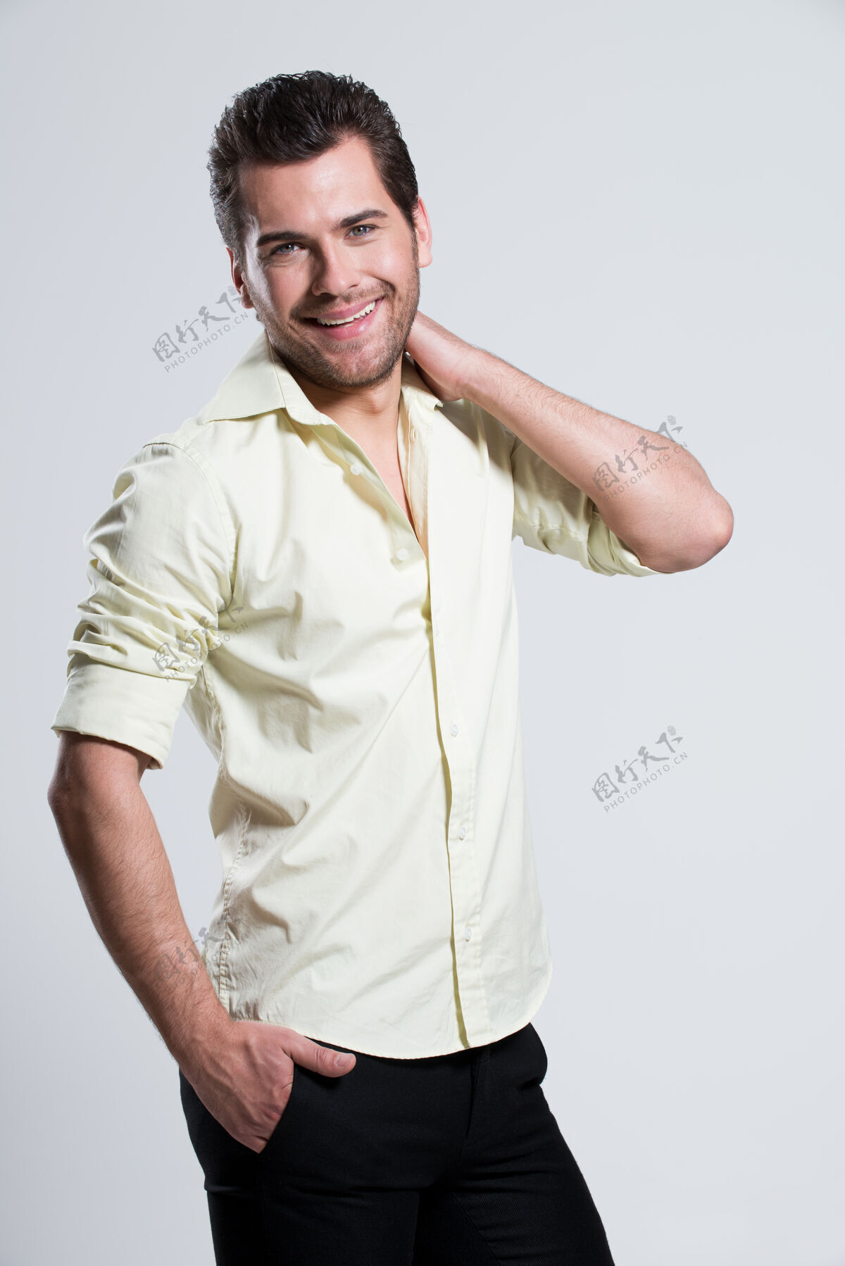 男人穿着黄色衬衫的帅哥快乐男人的时尚写真 手贴脸的姿势摆姿势微笑时尚