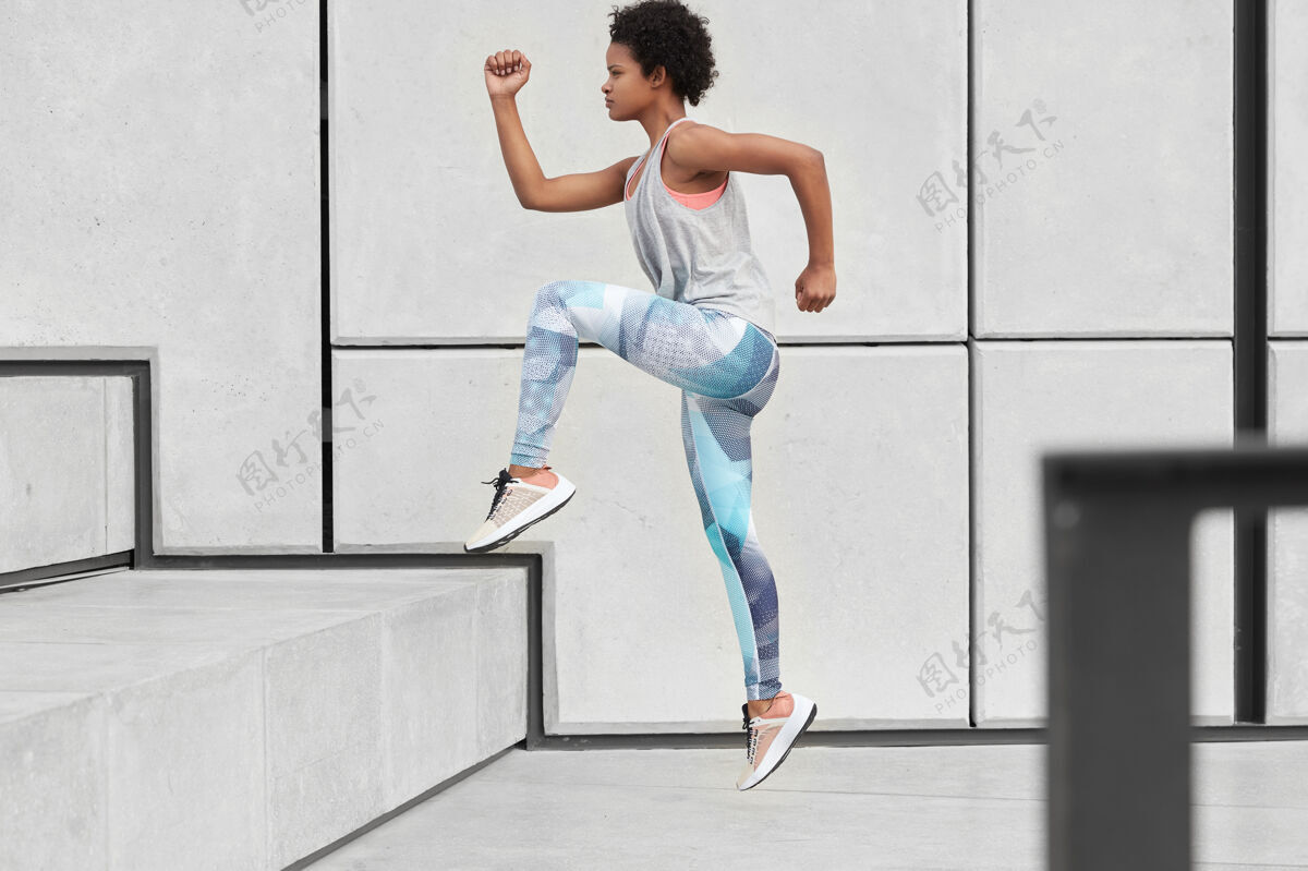 紧身裤健康健康的女人跑上楼梯 穿着舒适的衣服和运动鞋 慢跑锻炼 在城市环境中做运动 速度快 侧摆姿势健康和决心的概念女人休息挑战