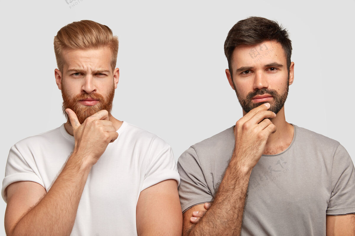 发型照片中严肃的两个男人抱着下巴 穿着休闲t恤 模特靠着白墙 陷入沉思 想办法解决问题姜男和他的朋友在室内摆姿势站剃胡子胡须