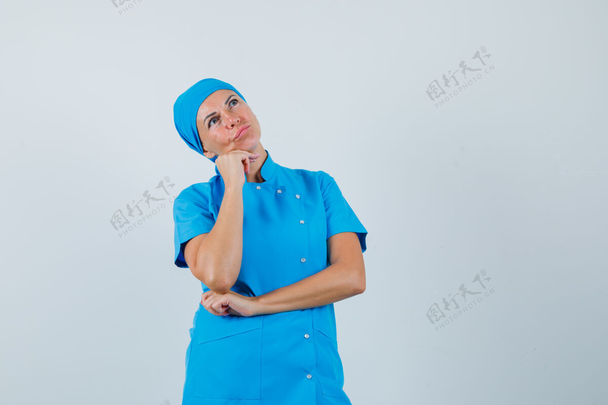 疾病女医生手托下巴 身穿蓝色制服 面带沉思 俯视前方站立治疗制服
