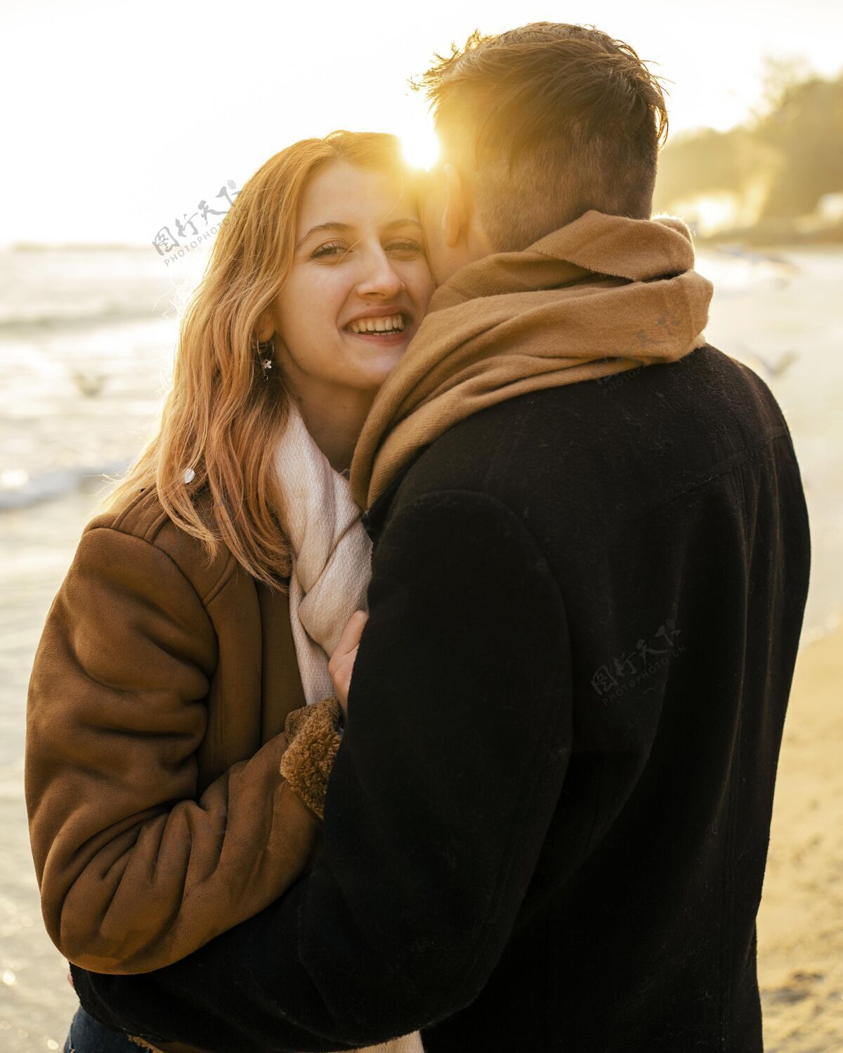 男人微笑的女人和她的男朋友在冬天的海滩上情侣冬天休闲
