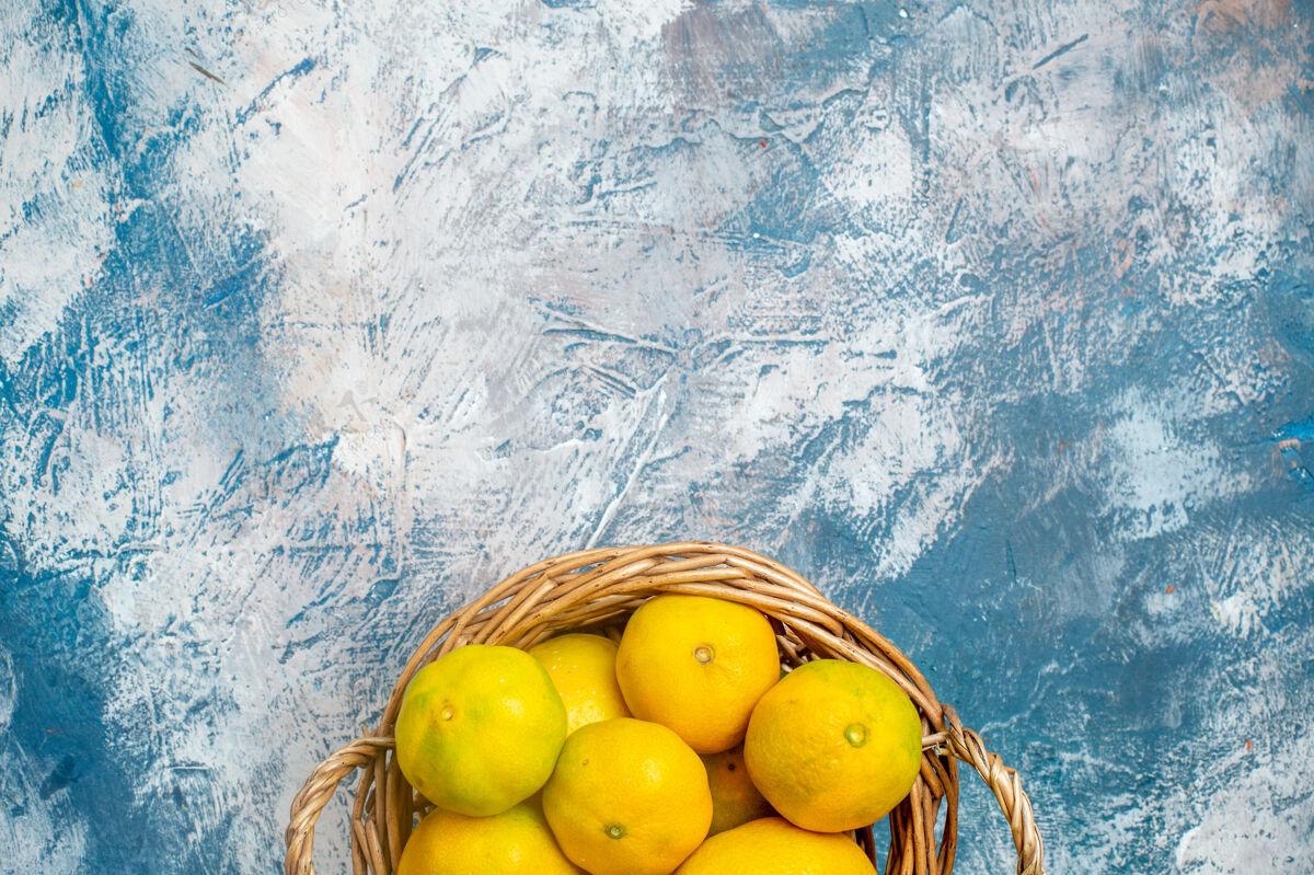 柠檬上半部分查看新鲜的柳条篮子在蓝白表面与复制空间的柑桔多汁顶部维生素