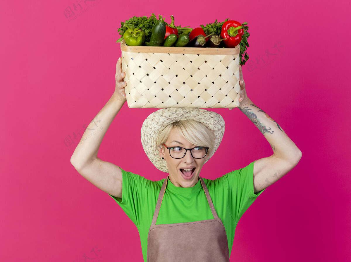 短裤一位年轻的园丁 围着围裙 戴着帽子 手里拿着装满蔬菜的箱子板条箱蔬菜持有