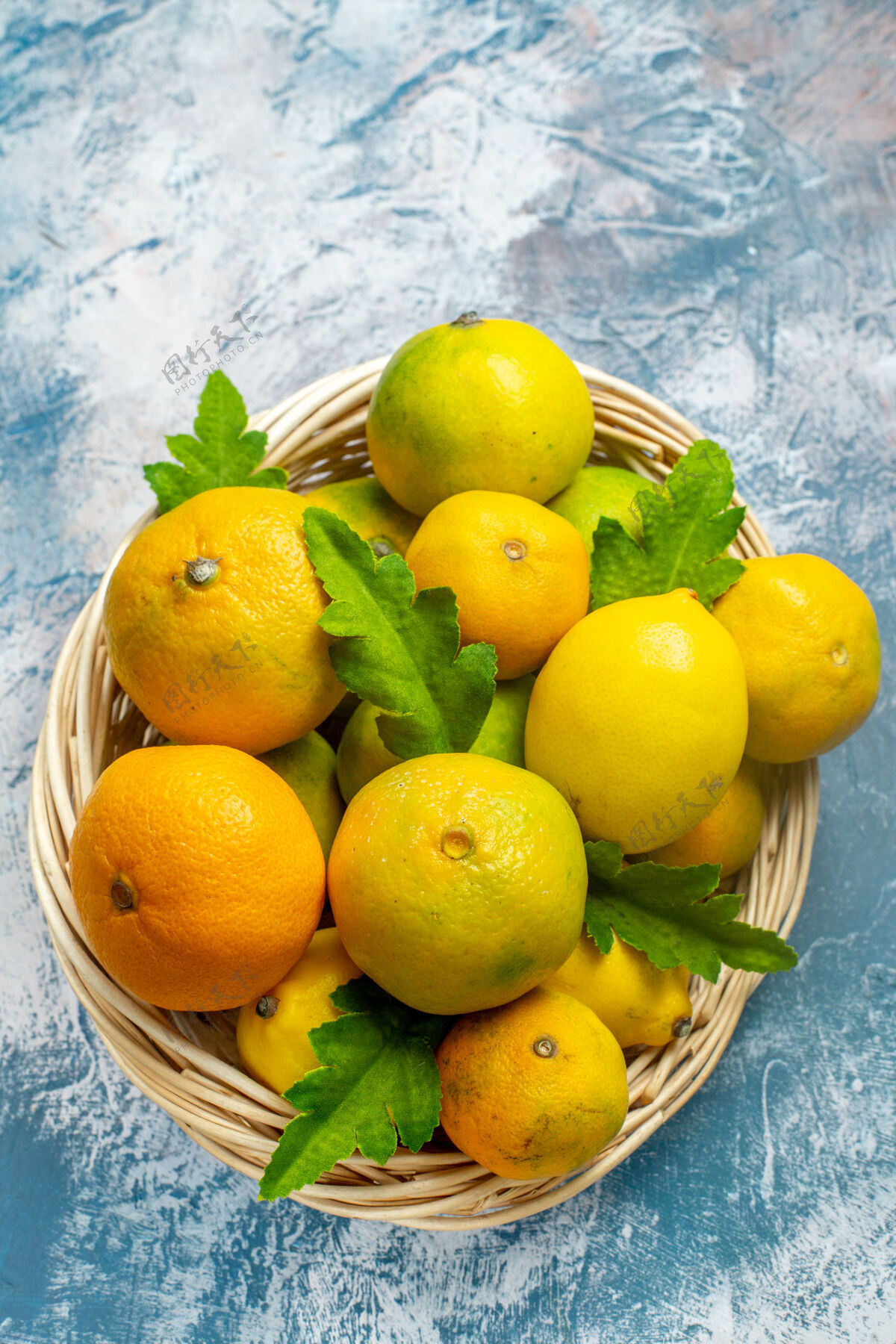 柑橘俯瞰蓝白色表面柳条篮子上的新鲜柑桔观点柳条维生素