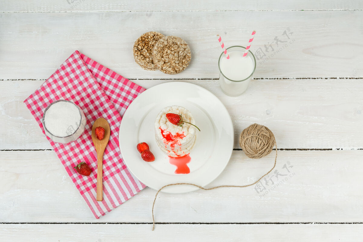 开胃菜顶视图白色的米糕和草莓放在盘子里 红色的方格桌布 木勺和奶制品放在白色的木板上水平蛋糕桌布木头