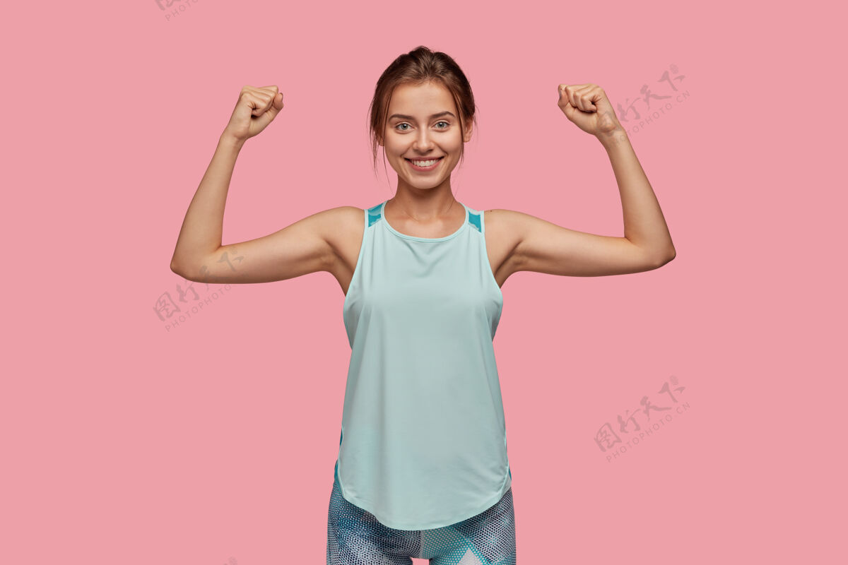欧洲腰部向上拍摄的运动女性举手展示她的肌肉朋友运动姿势